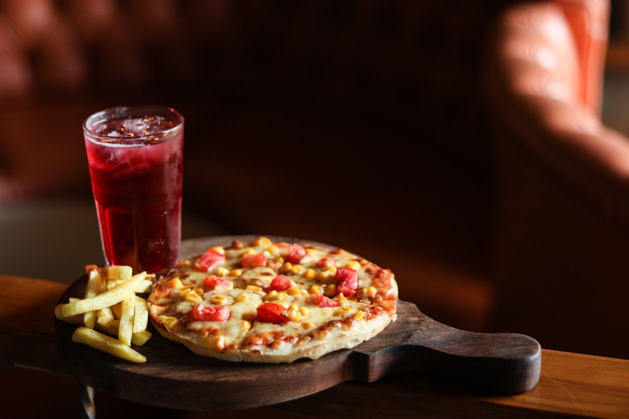 Tasty pepperoni pizza with fries and a refreshing drink on a wooden board.