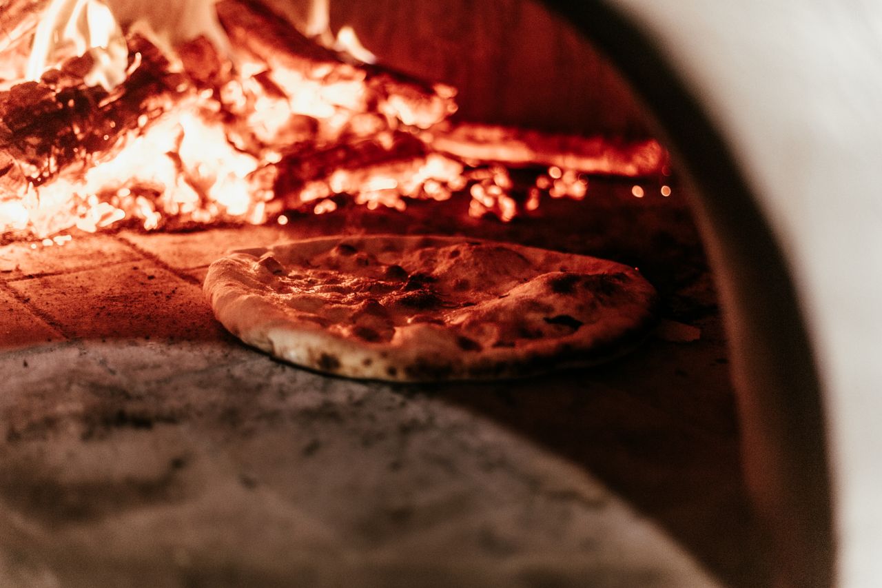 Close-up of a pizza baking in a traditional wood-fired oven.
